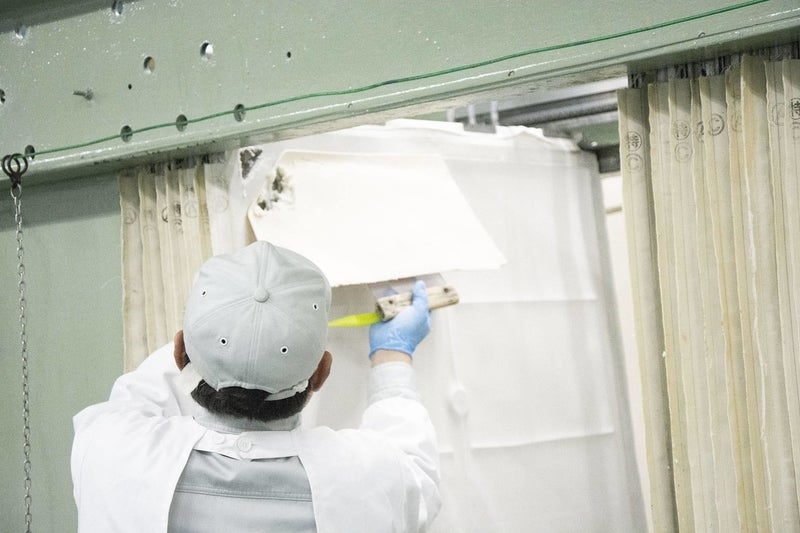 Sake lees being peeled off during the sake production process.