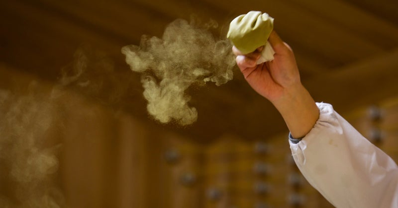 Sake lees being peeled off during the sake production process.
